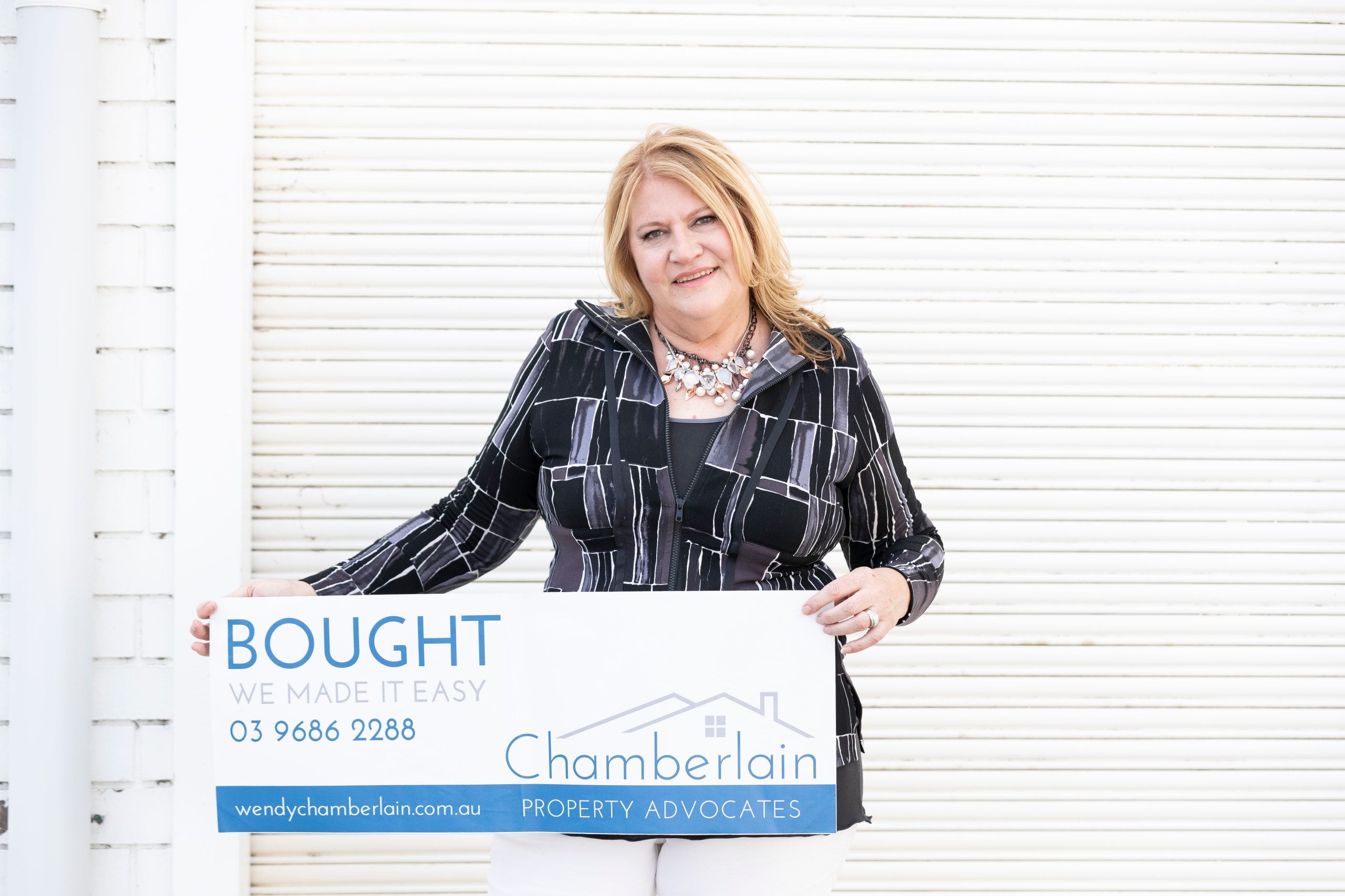 Wendy Chamberlain Melbourne Buyers advocate holding a Chamberlains BOUGHT sticker